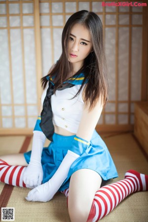 A woman in a blue skirt and white top posing for a picture.