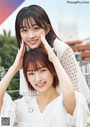 Two young women standing next to each other on a wooden deck.