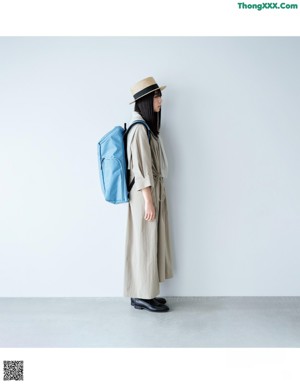 A woman wearing glasses standing in front of a white wall.