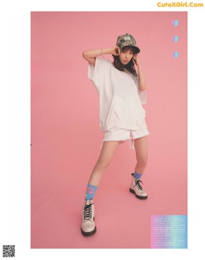 A woman in a pink shirt and shorts posing for a magazine.