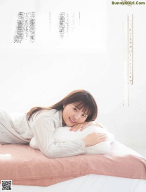 A woman sitting on a bed holding a pillow.