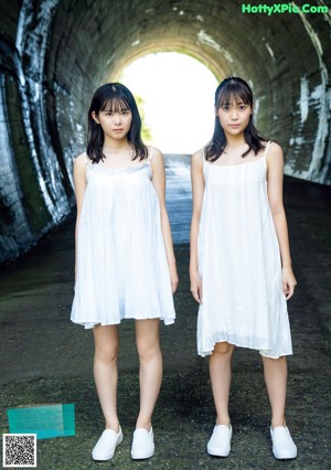 A couple of young women standing next to each other near a pool.