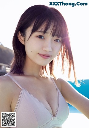 A woman in a white sweater is standing on the beach.