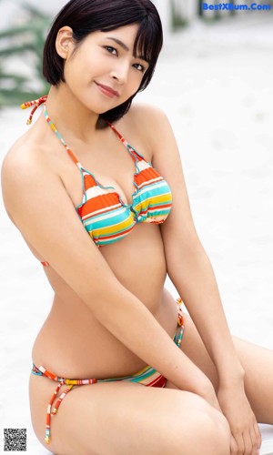 A woman in a black one piece swimsuit leaning against a wall.