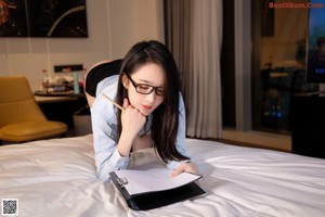 A woman sitting on top of a bed holding a folder.