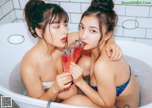 A couple of women standing next to each other in a bathroom.