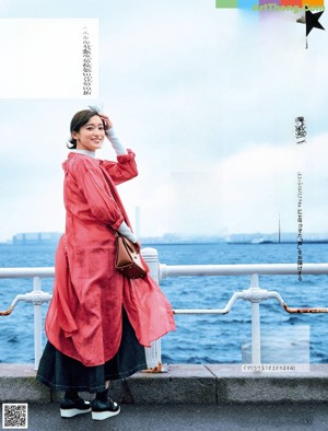 A woman in a red jacket eating a piece of food.