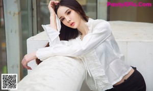 A woman in a white blouse and black pants posing for a picture.