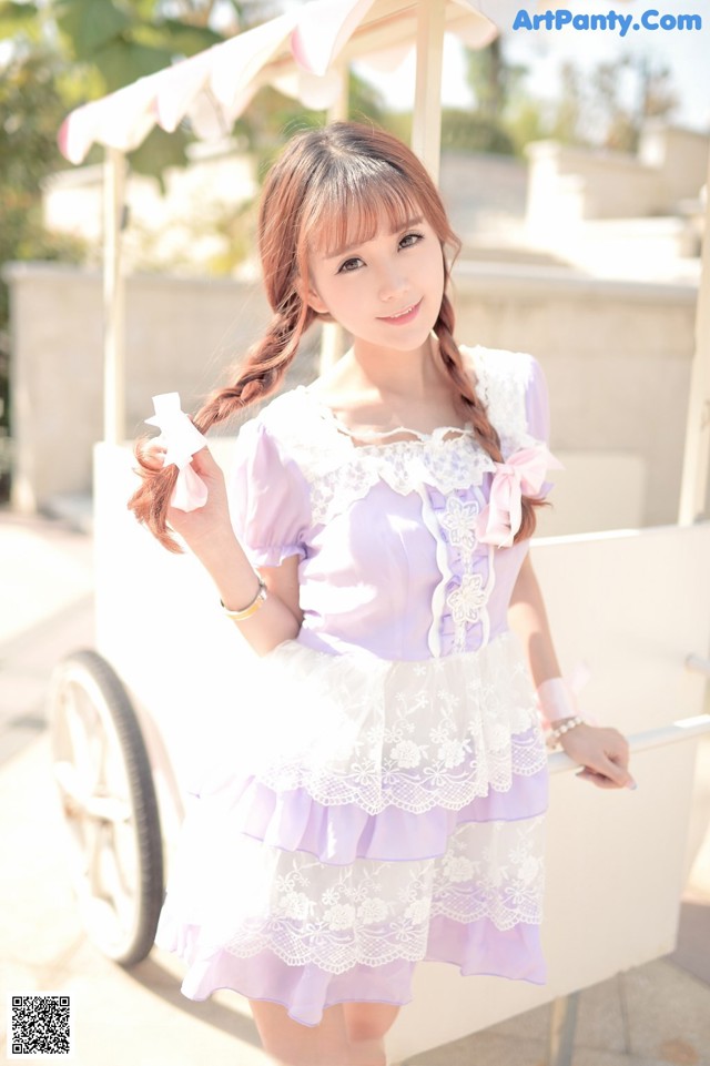 A woman in a purple and white dress posing for a picture.